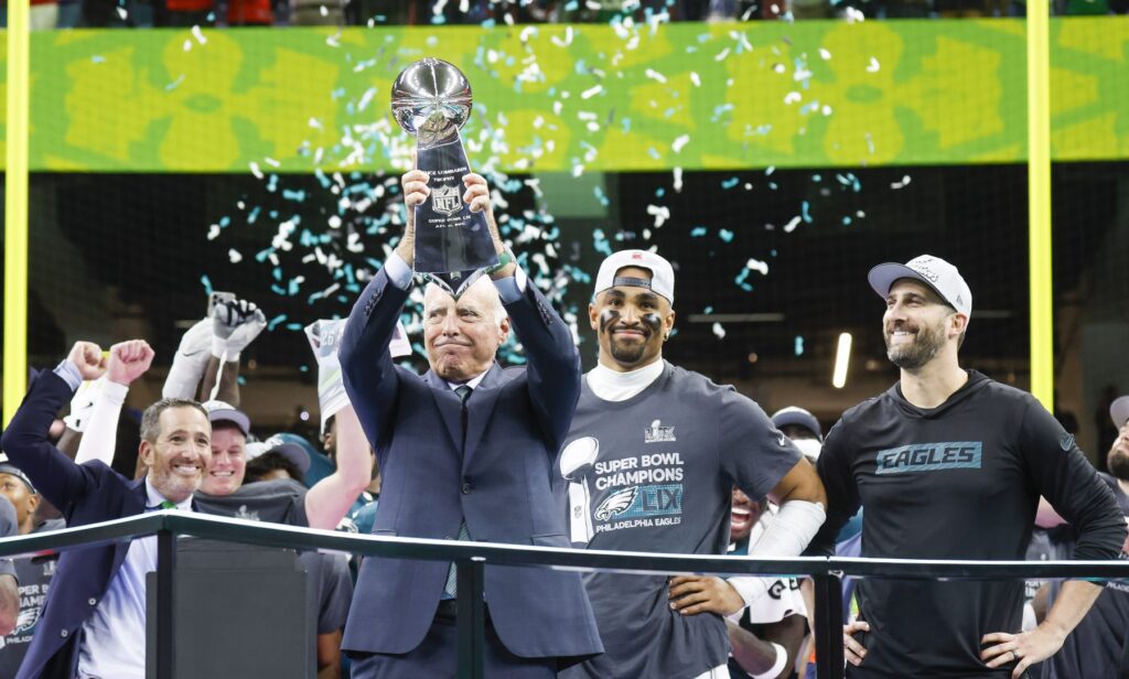 Philadelphia Eagles owner Jeffrey Lurie is presented the Vince Lombardi Trophy as quarterback Jalen Hurts and head coach Nick Sirianni look on during celebrations after the Eagles defeated the Chiefs 40-22 in Super Bowl LIX at Caesars Superdome in New Orleans on Sunday, February 9, 2025